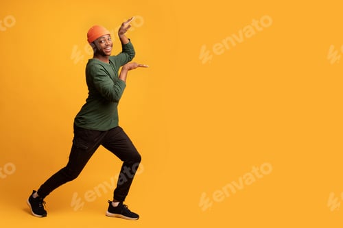 Preview: Cheerful Funny African American Guy Having Fun And Fooling Over Yellow Background