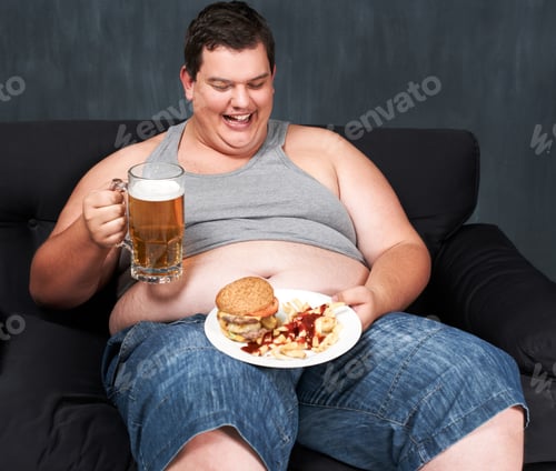 Preview: An obese young man sitting on a sofa and gorging himself on beer and fast food