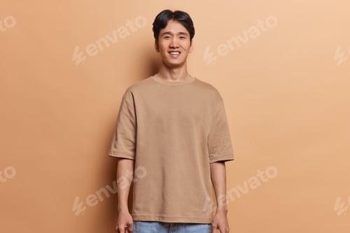 Preview: Studio shot of handsome cheerful Japanese adult man looks happily at camera keeps arms down dressed