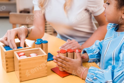 Preview: Selective focus of kid and teacher playing educational game at desk in montessori school