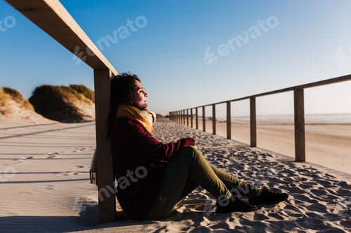 Preview: young woman with eyes closed relaxing at beach at sunset. Holidays and relaxation concept