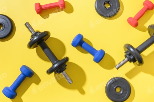 Preview: Set of dumbbells on yellow background. Top view, copy space.