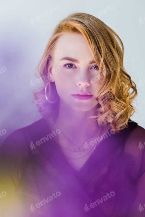 Preview: selective focus of beautiful young woman looking at camera on grey