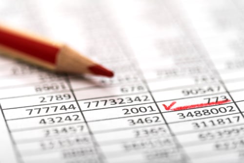 Preview: Closeup of a paper with calculations next to a red pencil
