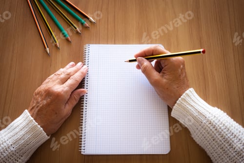 Preview: Close-up of mature woman hands with pencil writing on notebook