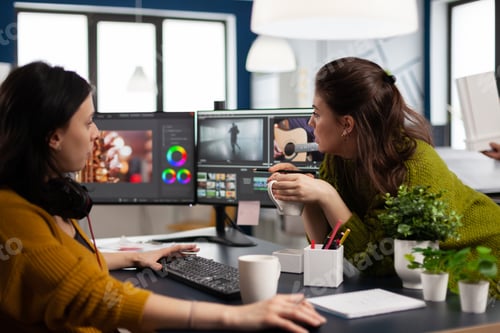 Preview: Coworkers video editors discussing in front of pc working for client footage