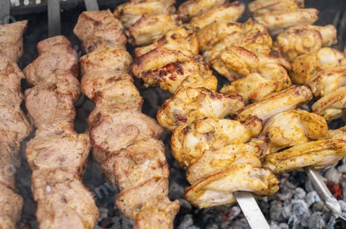 Preview: Shish kebab from different types of meat on skewers is fried on fire and coals in the grill