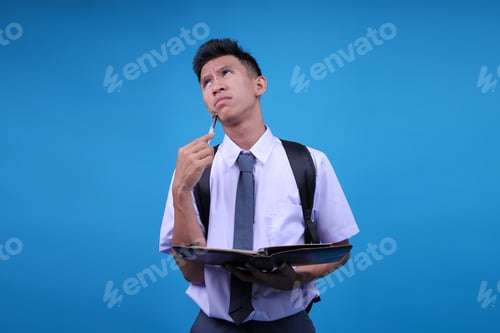 Preview: Pensive Indonesian High School Student Male With Backpack Write In Notebook Diary Prepare For Exam