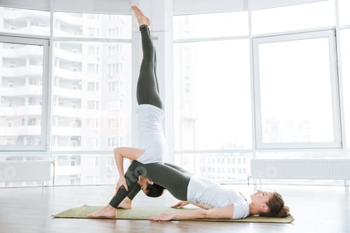 Preview: Two women doing balancing pose on pink yoga mat