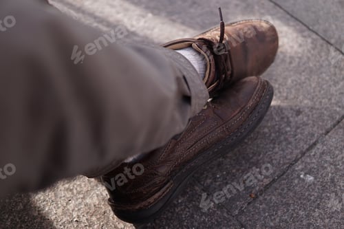 Preview: Closeup of the man's feet wearing brown shoes.