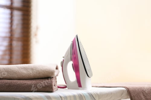 Vista previa: Modern iron and towels on board in room. Space for text