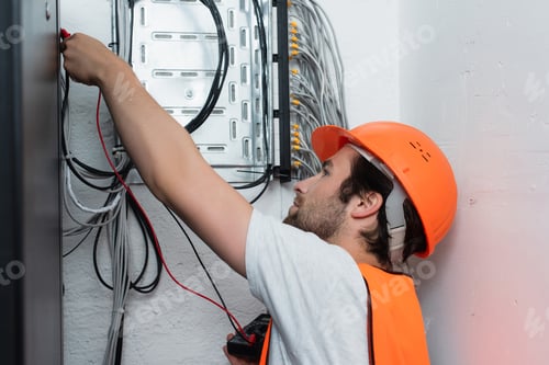 Preview: Side view of workman holding electrical tester near switchboard