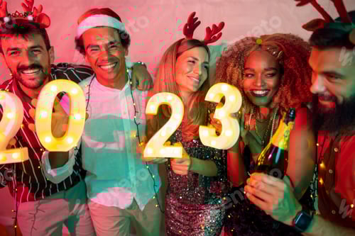 Visualização: Amigos segurando números iluminativos de 2023 na festa de Ano Novo