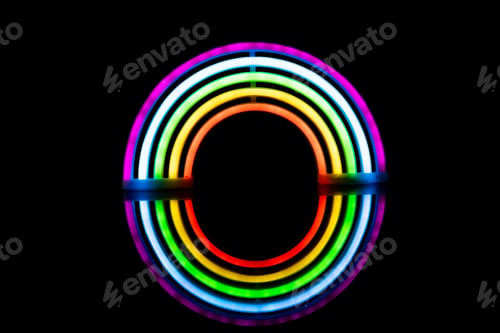 Preview: Image of vibrant neon glow sticks forming rainbow with reflection on black background and copy space