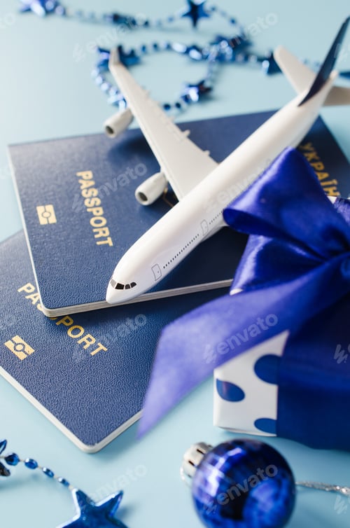 Preview: Christmas travel planning. Traveling as gift. Model of passenger plane, passports and gift box.