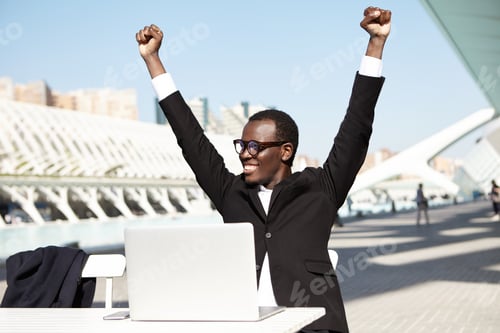 Preview: Hurrah! Successful businessman in formal clothes raising his hands having cheerful expression after