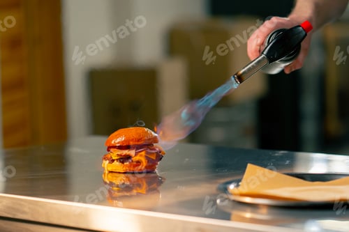 Preview: close up in a professional kitchen in pizzeria the chef burns a burger with a gas burner on the