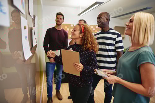 Preview: Smiling coworkers going over paperwork together on an office wall