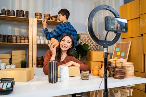 Preview: Attractive man and woman sell vase product online live stream at home.