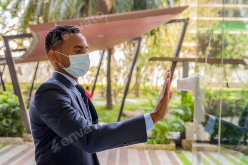 Preview: African businessman with surgical medical mask measuring body temperature