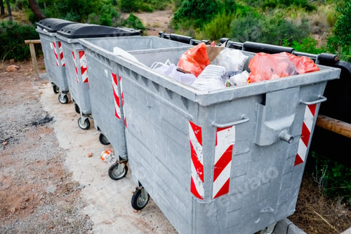 Preview: Metal garbage containers for urban waste in a field area.