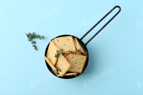 Preview: Tasty salty crackers and thyme on light blue background, top view