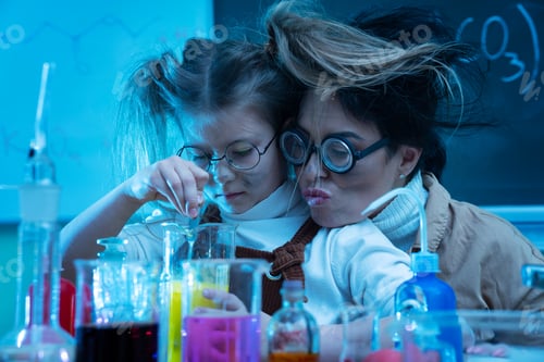 Preview: Teacher and little girl during chemistry lesson mixing chemicals in a laboratory
