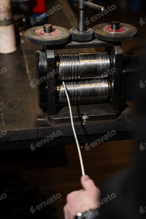 Preview: Jeweler drawing gold through rolling mills to produce wire or thin strips.