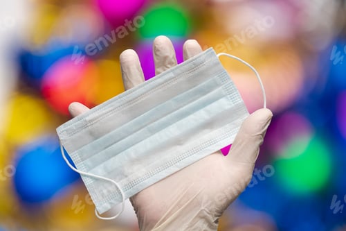 Preview: Doctor holds medical face mask in hand in white medical gloves on Xmas balls decorations background
