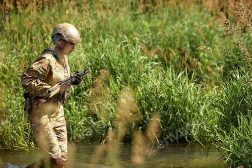 Preview: Portrait of fit military female holding weapon rifle in hands in river, posing alone. Confident