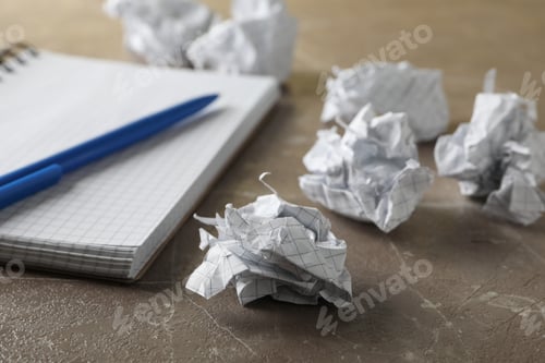 Preview: Paper balls, notebook and pen on grey table, close up