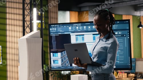 Preview: Black real estate engineer works with 3D towers and digital blueprints