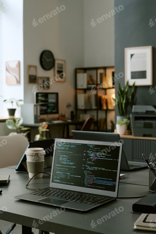 Preview: Modern Office Workspace Featuring Laptop Displaying Programming Code