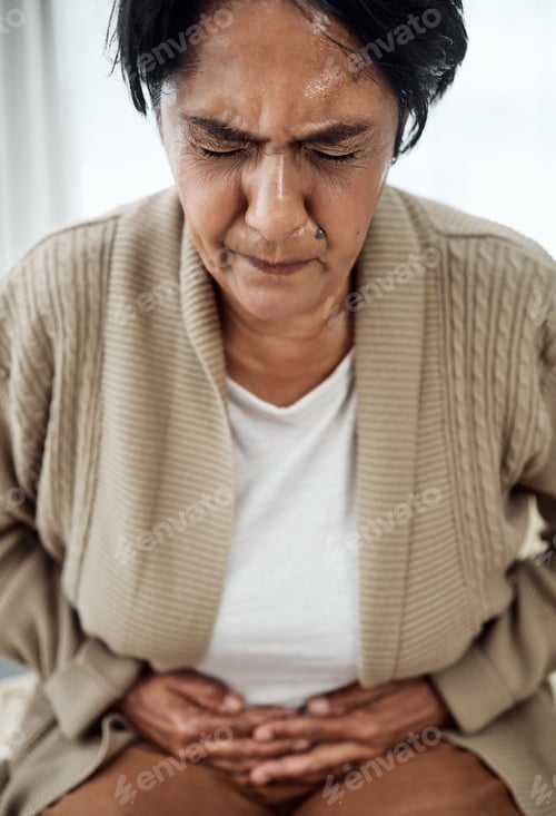 Preview: Stomach pain, sick or illness with a senior woman in her home, holding her belly in discomfort. Hea