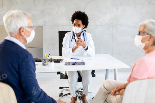 Preview: Senior couple with protective facial masks receive news from black female doctor