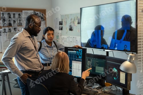 Preview: Mature FBI agent showing two young subordinates photo of criminal on screen