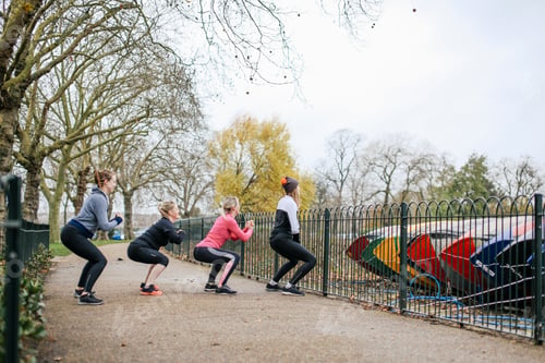 Preview: Women and teenage girl doing warm up squats in park