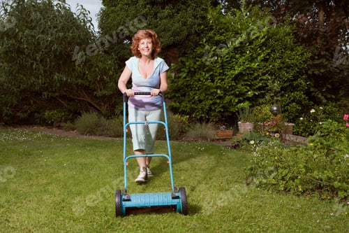 Preview: Mature woman mowing lawn