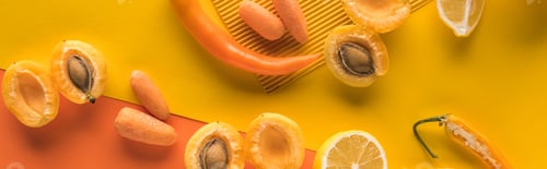 Preview: top view of yellow fruits and vegetables on orange background, panoramic shot