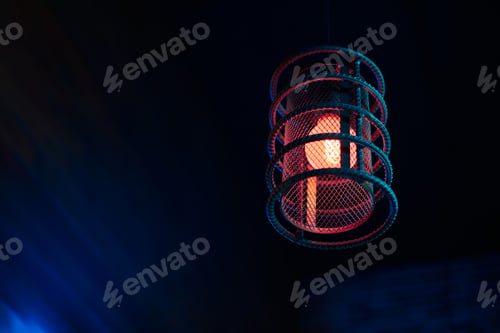 Preview: Loft pendant lamp with red blue glow in steel rebar shade, wooden interior background, copy space