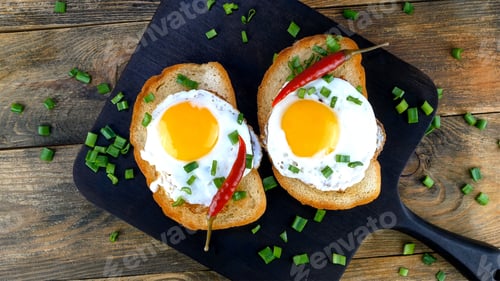 Preview: Fried egg sandwich with yolk on toasted slice of bread sprinkled with green onions.