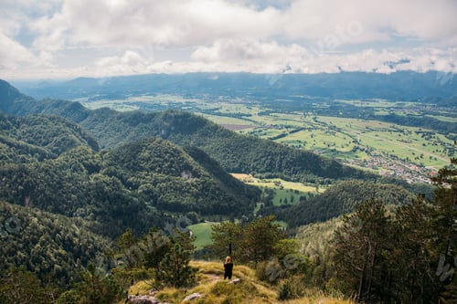 Preview: Woman hiker at the top of the hill with beautiful views of the vast landscape below.