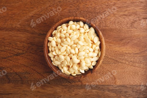 Preview: Wooden bowl of depilation wax beans on wooden background.