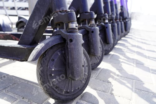 Preview: A row of wheels of scooters with scratches on them in the street standing ready for rent