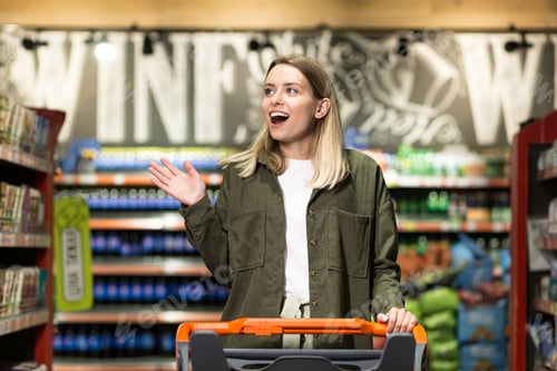 Preview: young happy woman pushing trolley spends time in a supermarket or mall store.