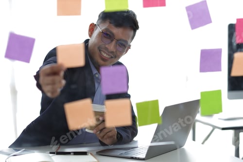Preview: Businessman thinking and planning work with sticker on glass plate in office.