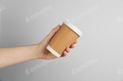 Preview: Woman holding paper cup on grey background, closeup. Mockup for design
