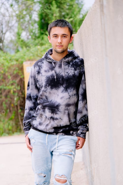 Preview: Teenager leaning on a fence wearing sweatshirt and jeans