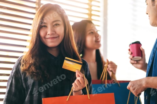 Preview: Woman with shopping bags holding and showing a credit card with friends in background