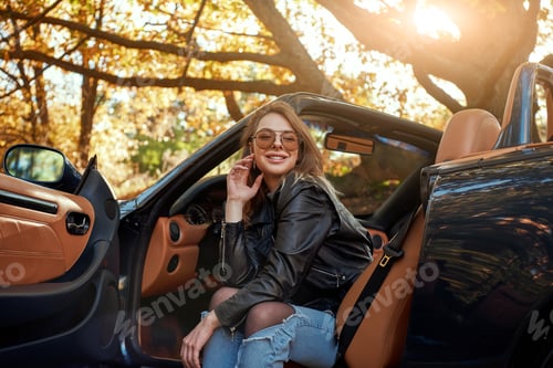 Preview: Sexy young woman in jeans smiling in a cabriolet